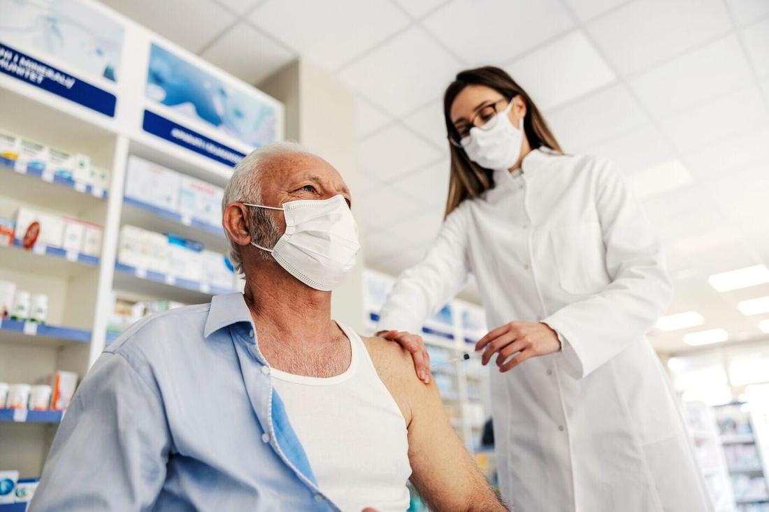 A pharmacist administers a vaccine to an older man. Read the Canadian Healthcare Network op-ed.